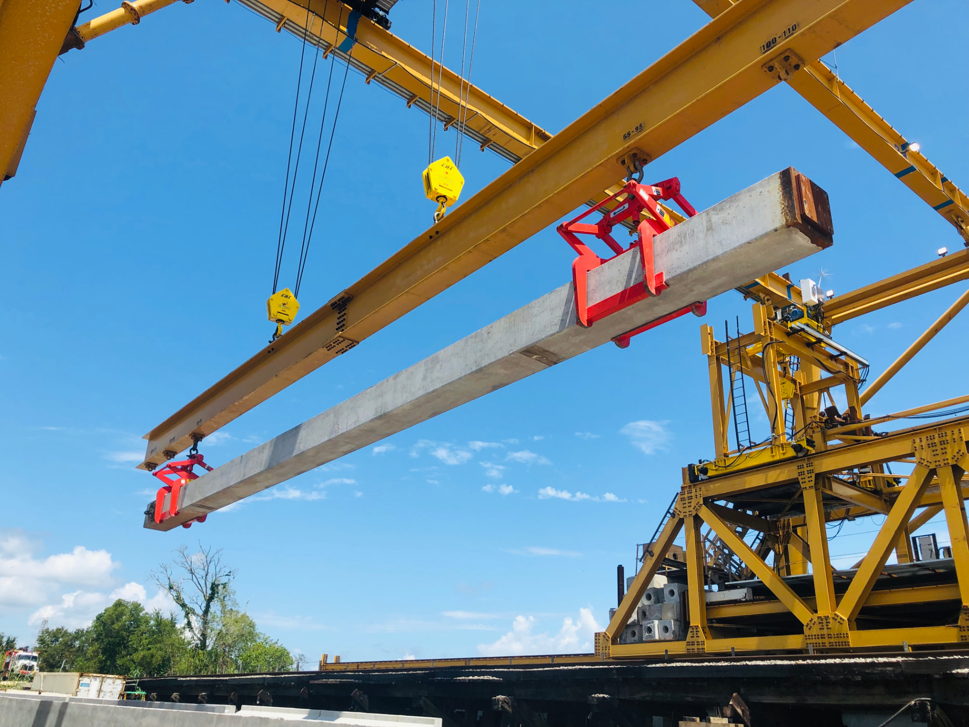 Gantry crane lifting a prestressed concrete pile section on a construction site